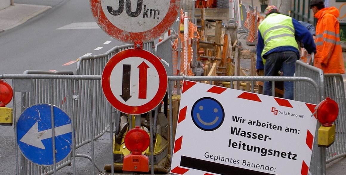 Strassenbaustelle mit Bauarbeitern und Warnschild.