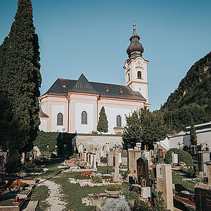 Der Friedhof sowie die Kirche von Gnigl, fotografiert vor einem wolkenlosen, blauen Himmel.