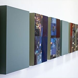 Foto der ausgestellten Collagen die nebeneinander an einer Wand aufgehängt sind.