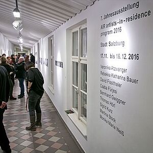 Gangbereich mit interessierten Besuchern; an den Wänden die Ausstellungsobjekte