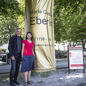 Fred Kendlbacher und die Künstlerin Maria Hanl neben ihrer Litfaßsäule mit der Hommage an die fast vergessene Komponistin Maria C. Eberlin am Franz-Josef-Kai 19. 