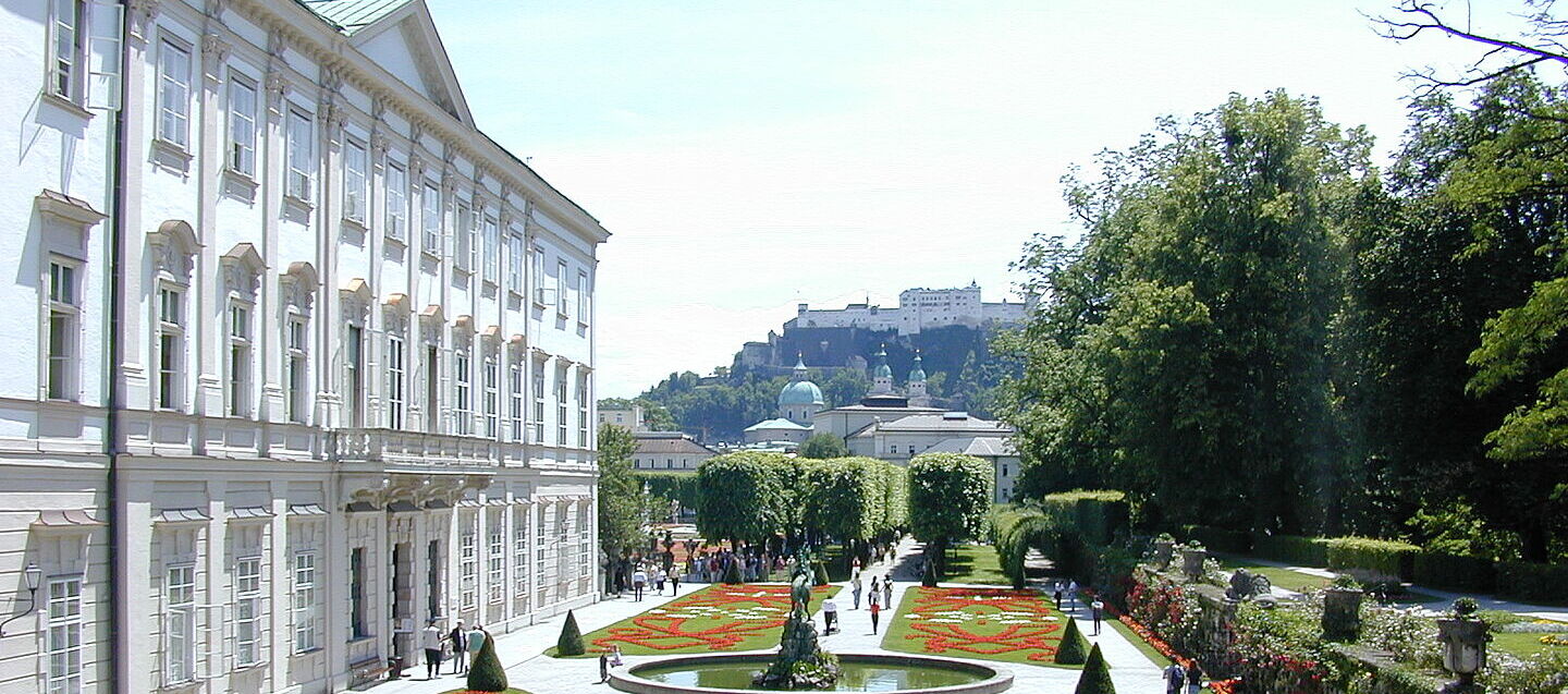 Das Schloss Mirabell mit Garten und der Festung im Hintergrund.