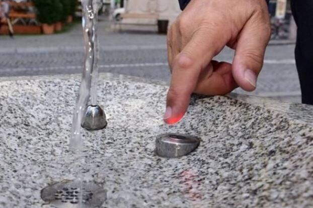 Ein Mann greift in das Frischwasser aus dem sensorgesteuerten Trinkwasserbrunnen in der Altstadt.