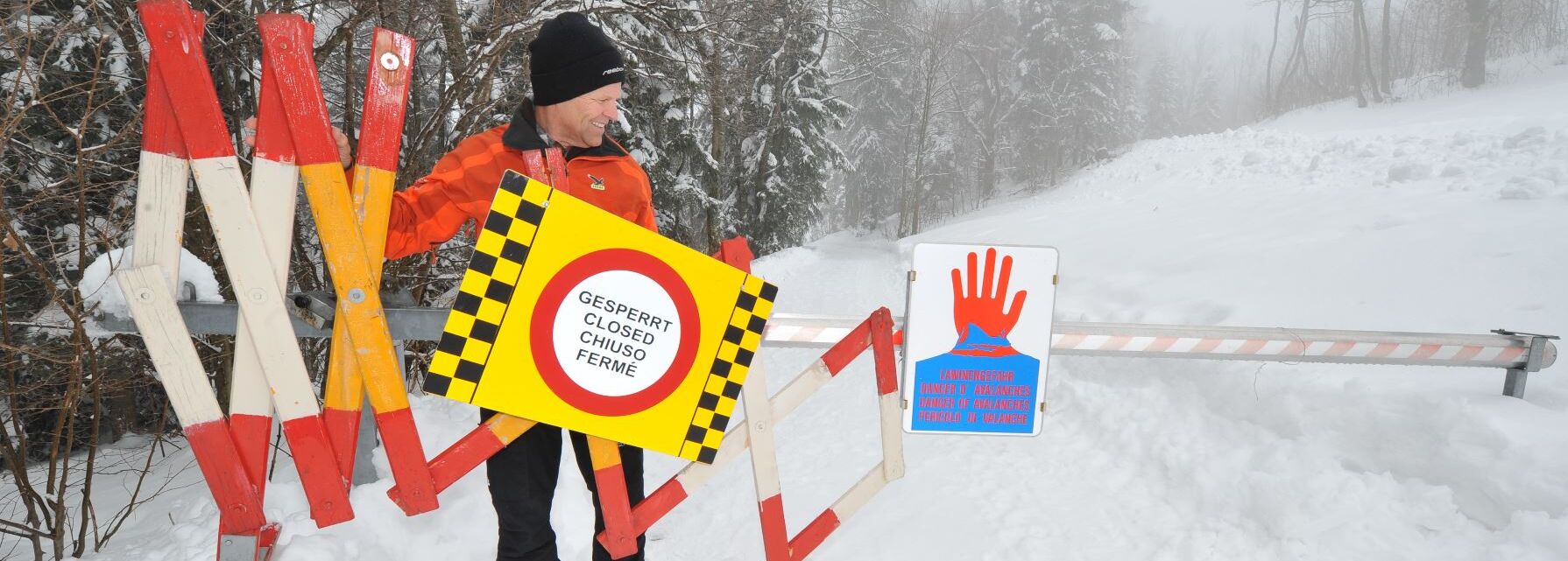 ein Warnschild füt Lawinengefahr und eine Apsperrung für den Rundwanderweg am Gaisberg im Winter