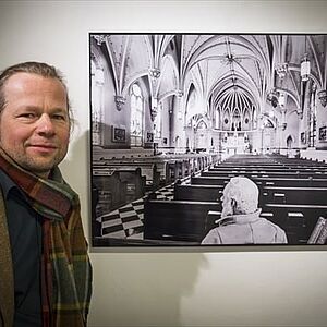 Der Künstler Konrad Rainer steht neben einem Bild mit dem Titel "Carnage Matters".