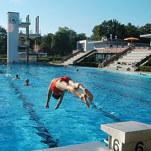 Ein Mann springt mit einem Koepfler in das Sportbecken des Leopoldskroner Freibades "Lepi".