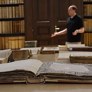 Ein Mann haelt einen Vortrag zum "Tag der Archive" in einem Archiv mit vielen Buechern.