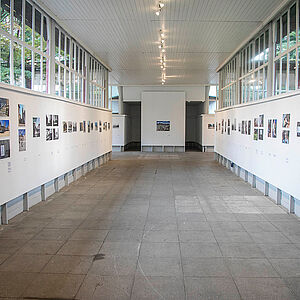 Foto eines Ausstellungsraumes des Zwergelgartenpavillons mit den Fotos an den Seitenwänden.