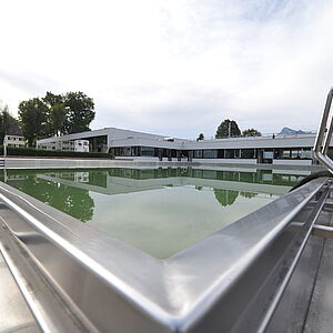 Blick über Freibecken zur neuen Schwimmhalle: