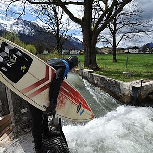 Ein Surfer hat sein Surfbrett in der Hand und will sich in die Wellen stuerzen.