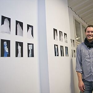 David Fisslthaler steht neben mehreren Fotogafien mit der Abbildung des "Negativraumes“ zwischen Gebäuden