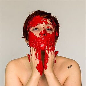 Ein Portrait einer Frau welche verschmierte, rote Farbe im Gesicht hat, gehörend zu Sarah Oswalds Projekt names fühlsprechen.
