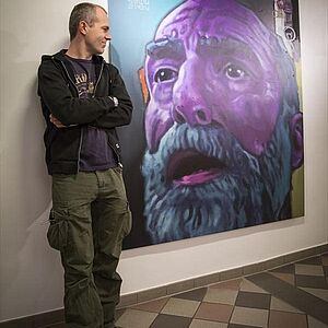 Der Künstler Stefan Kreiger steht neben seinem Bild mit dem Titel "Le roi est mort, vive le roi!"