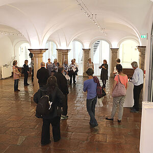 Foto von vielen Menschen in der Säulenhalle im Rathaus bei der Ausstellungseröffnung  