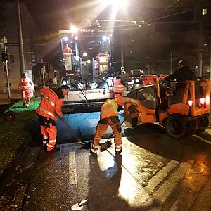 Deckschichtsteinbau mit Fertiger bei Nacht