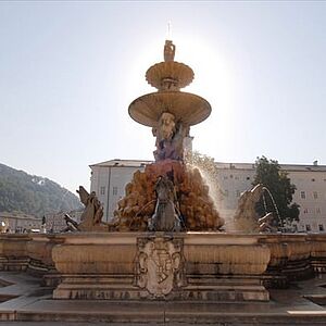 Der Residenzbrunnen vor blauem Himmel und der strahlenden Sonne.