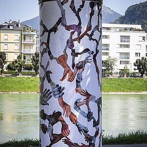 Das Werk names Social Network von Karin Fisslthaler auf einer Litfaßsäule vor der Salzach.