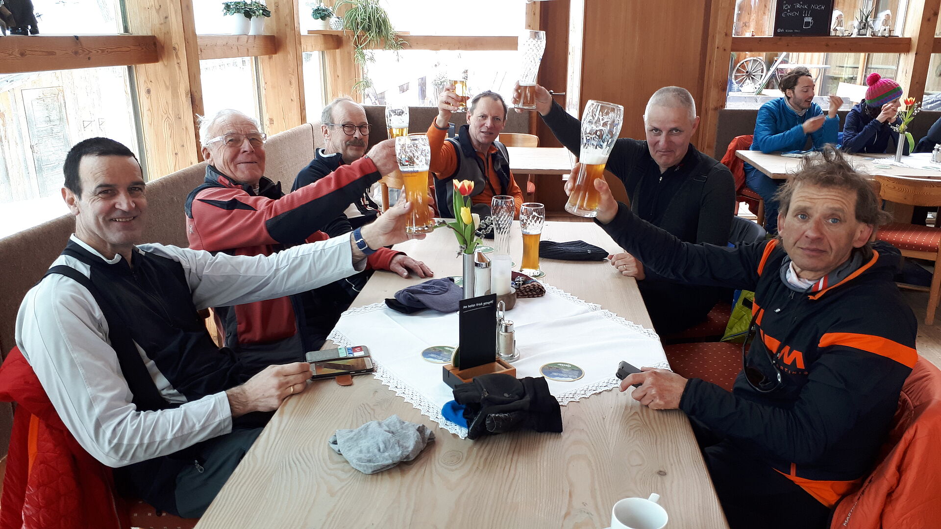 Tourenteilnehmer an einem Tisch erheben das Glas