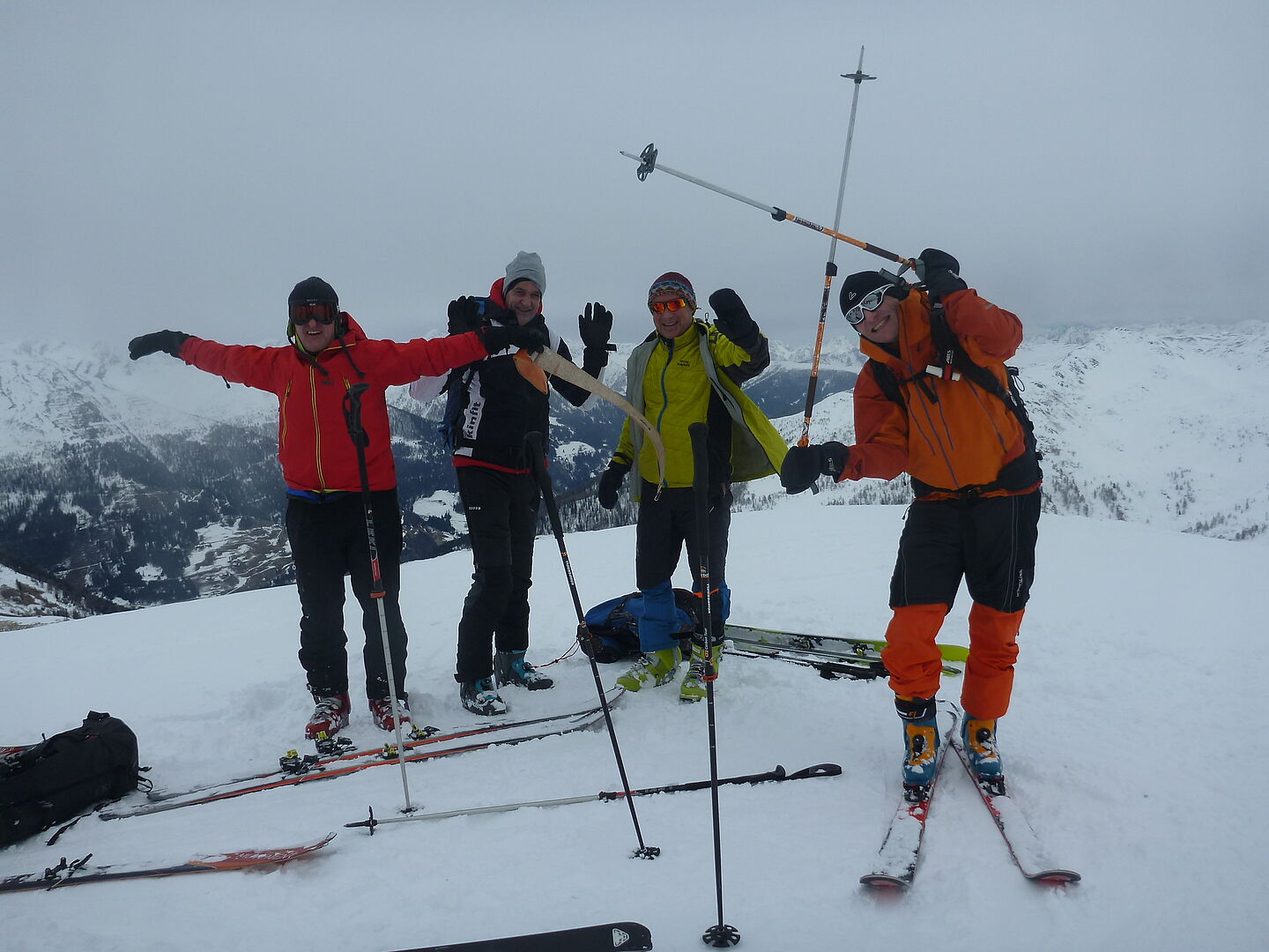 Vier Tourenteilnehmer am Grat des Gipfels, im Hintergrund die Berglandschaft im aufziehenden Nebel