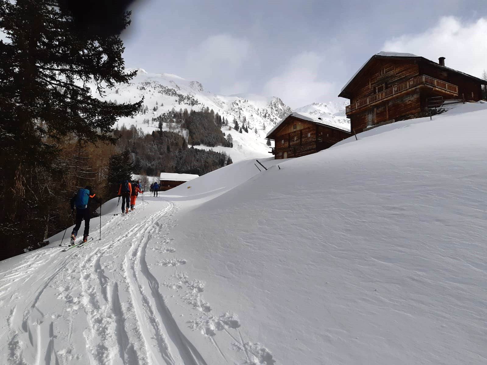 Die Tourengeher beim Aufstieg zu einem kleinen Dorf mit Holzhäusern