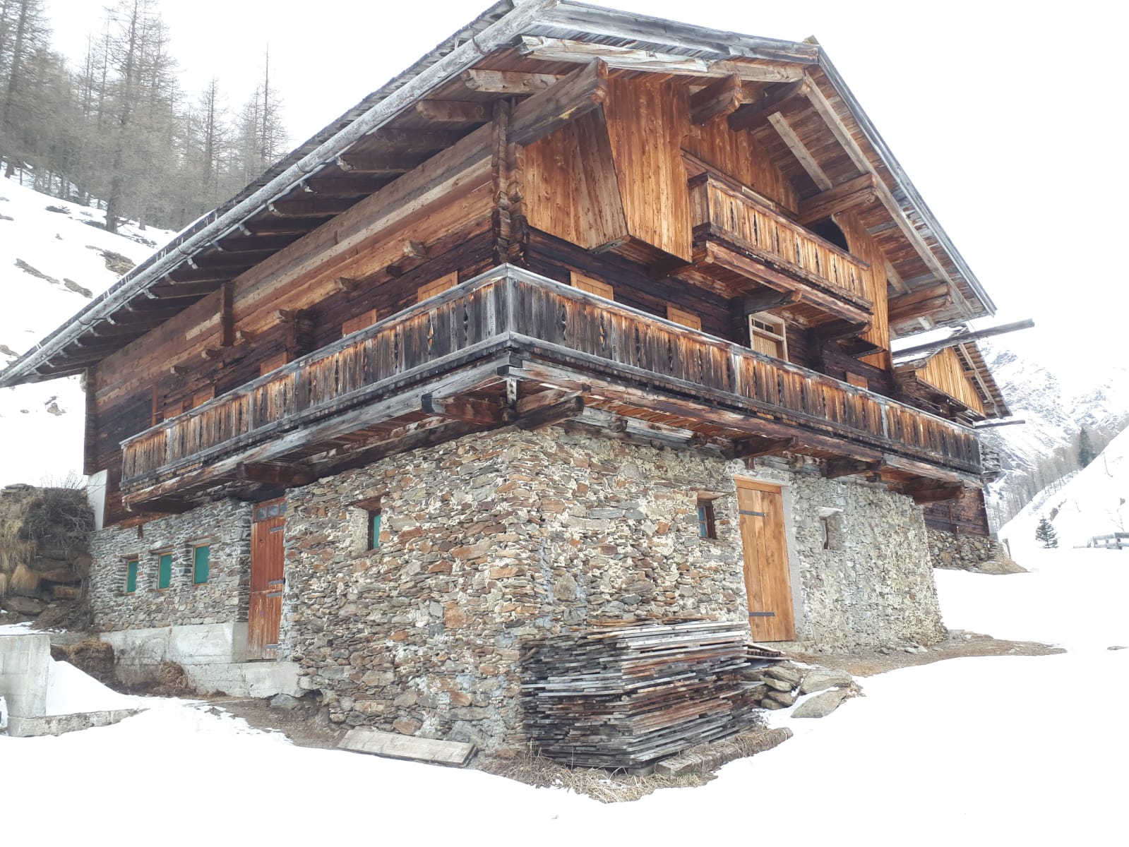 zwei Häuser nebeneinander: die Erdgeschoße aus Bruchsteinen und dem ersten Stock und dem Dachgeschoß aus verwittertem Holz