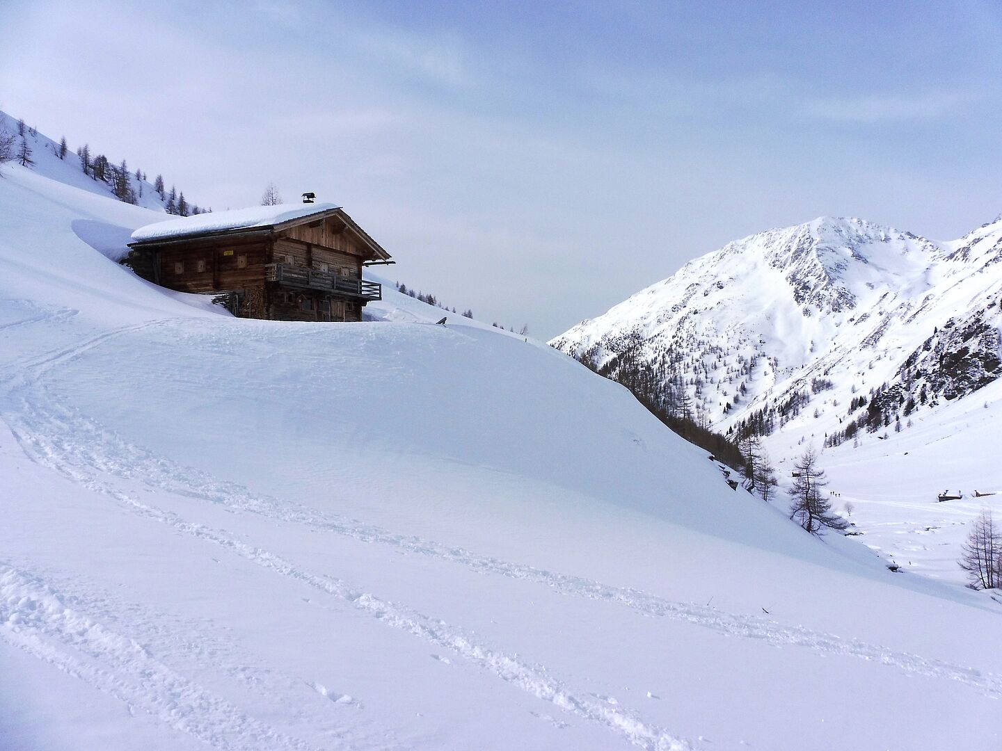 Einzlenes Holzhaus im verschneiten Berghang