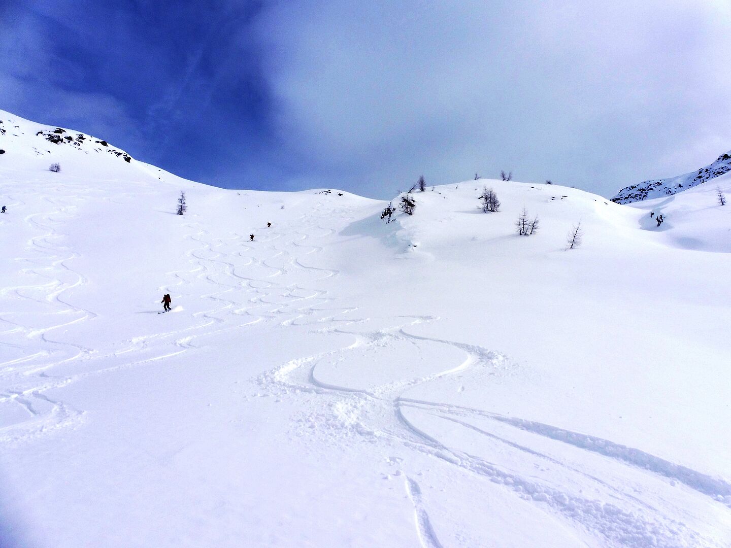 drei Tourenteilnehmer wedeln durch den Tiefschneehang