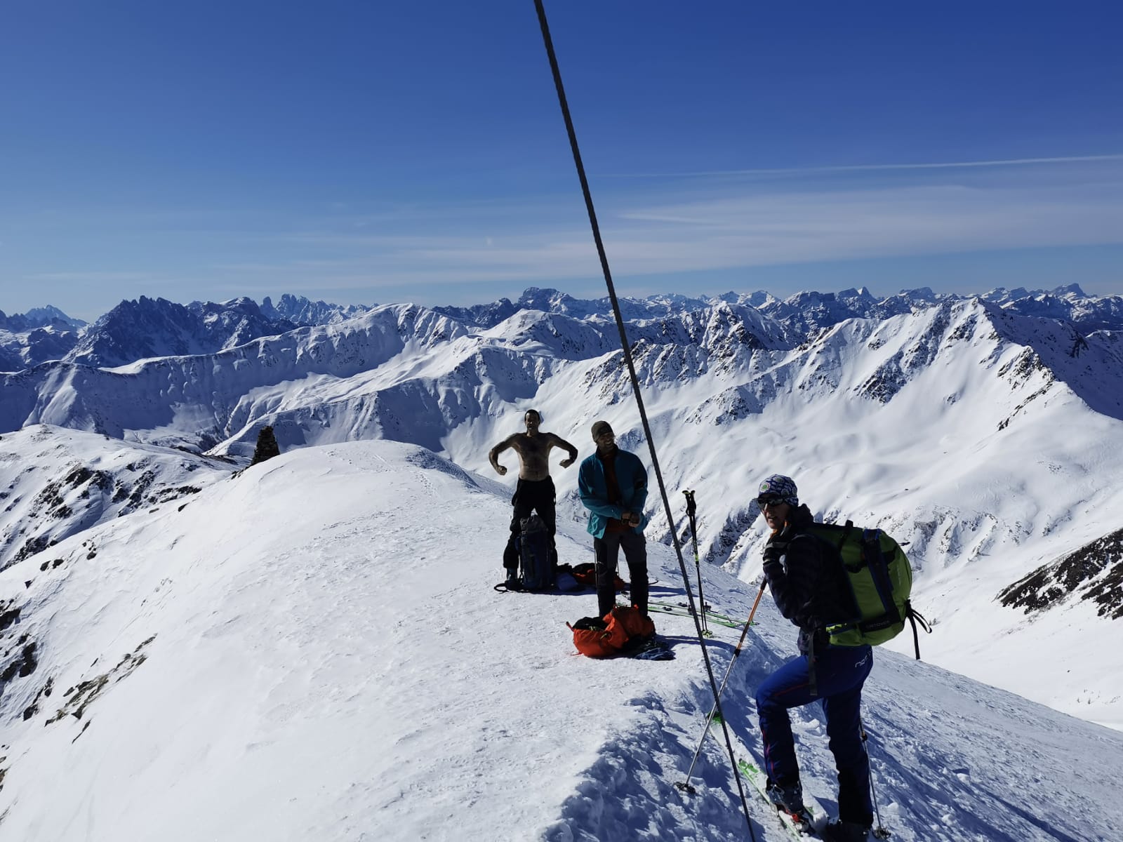 Tourenteilnehmer auf dem Gipfelgrat genießen den Ausblick auf die schneebedeckte Gebirgslandschaft