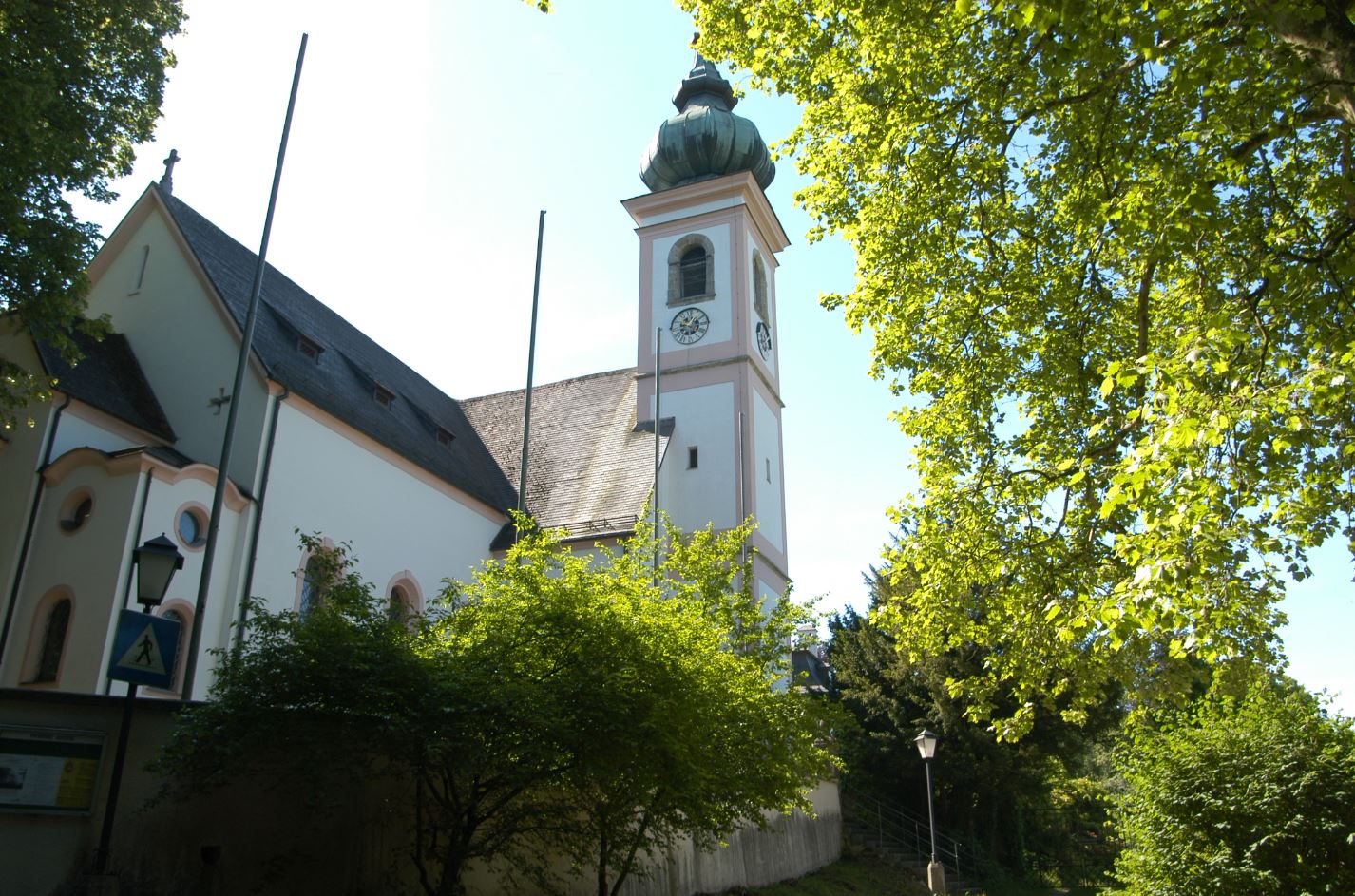 Die Kirche Schloss Aigen vor grünen Bäumen und Büschen.
