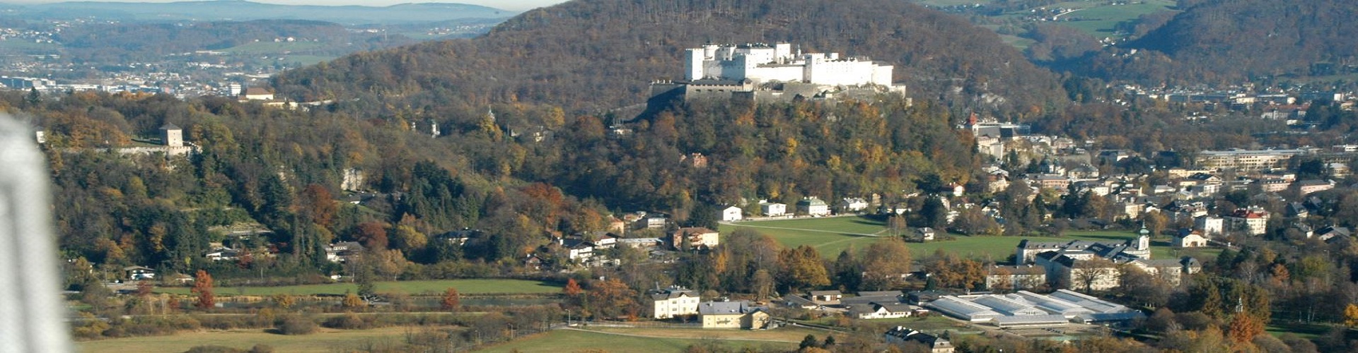 Eine Luftaufnahme von der Stadt Salzburg mit dem Festungsberg im Hintergrund.