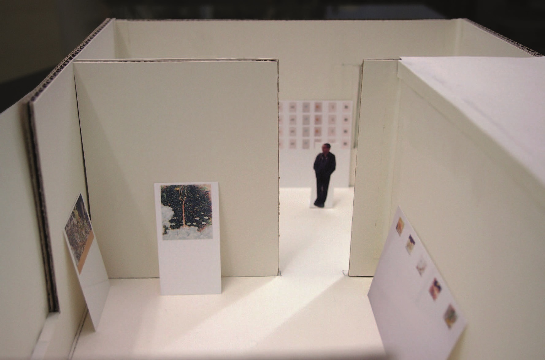 Foto von oben in das Karton-Modell in dem zwei Räume mit einer Öffnung verbunden zu sehen sind und an den Wänden der Karton-Räume lehnen die Werke des Küpnstlers, so wie sie dann in der Galerie aufgehängt werden. 