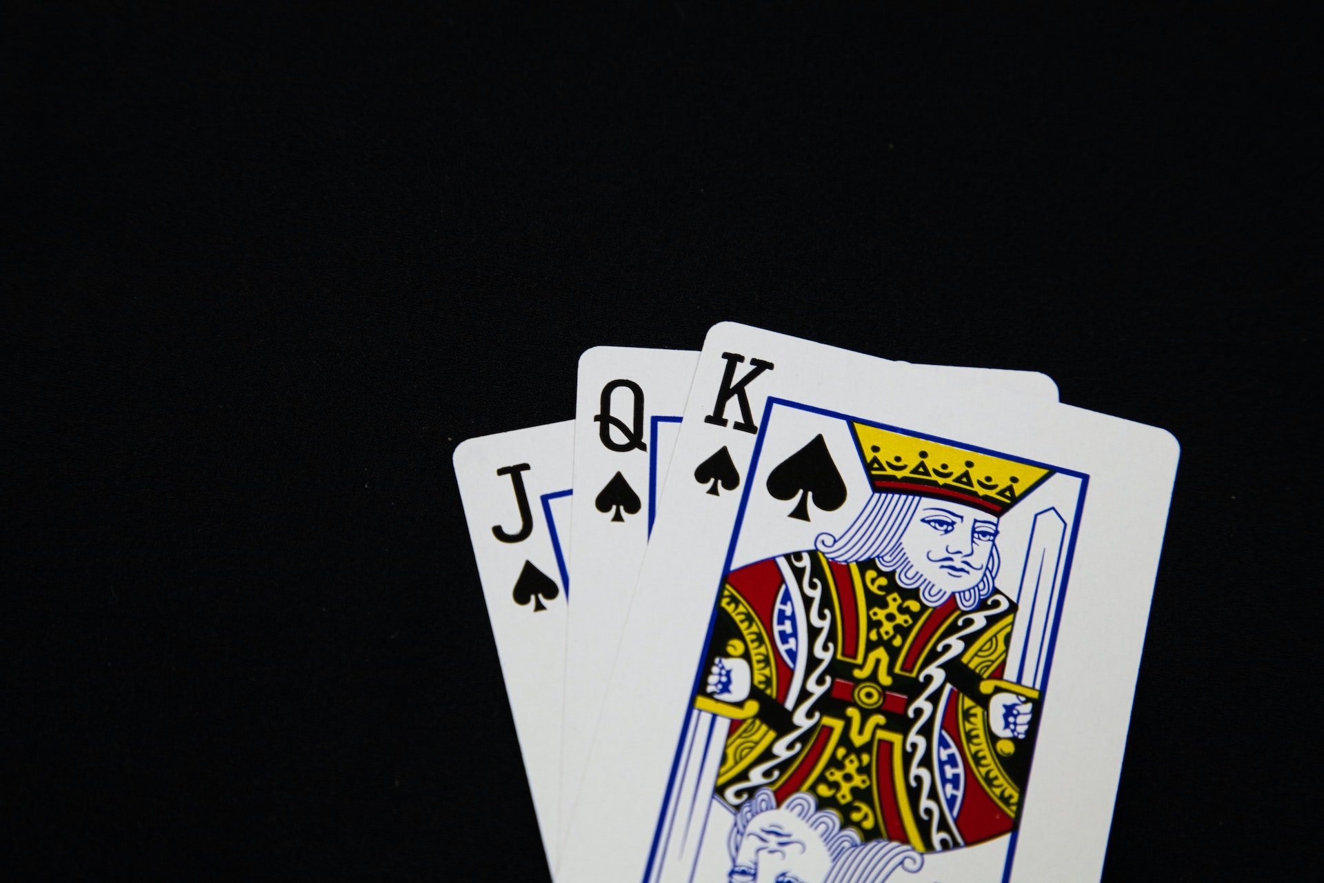 Drei aufgefächerte Spielkarten: Pik Bube, Pik Dame und Pik König