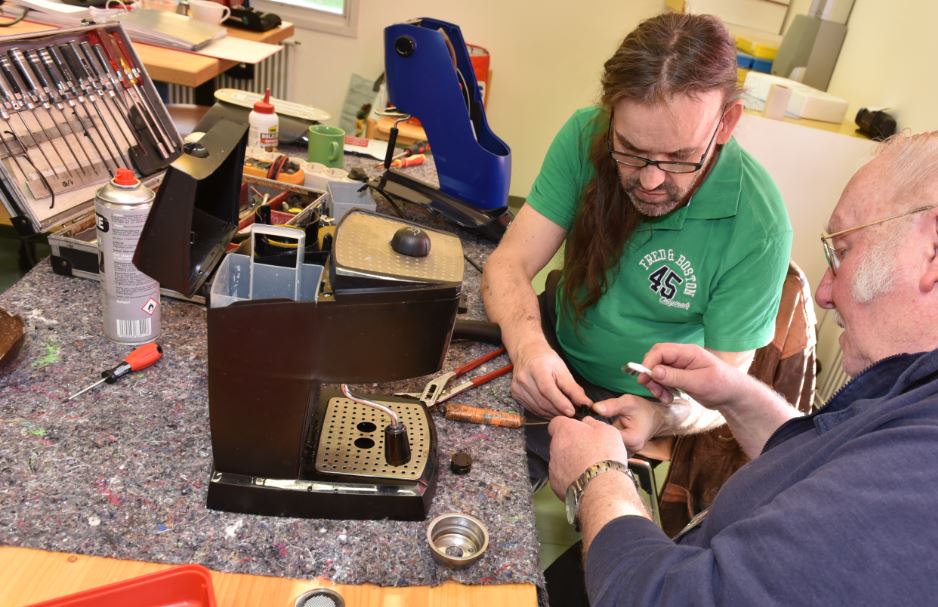 Zwei Männer reparieren im Repair Cafe kaputte Dinge.