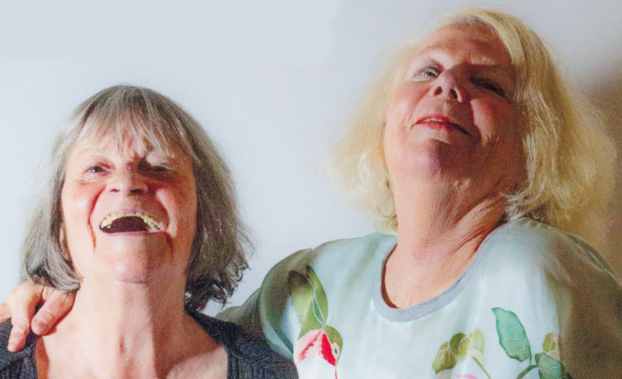 Jenny Simanowitz und Kathy Tanner die Künstlerinnen nebeneinander stehen im Halbportrait, wobei die Eine ihren Arm um die Schulter der Anderen gelegt hat