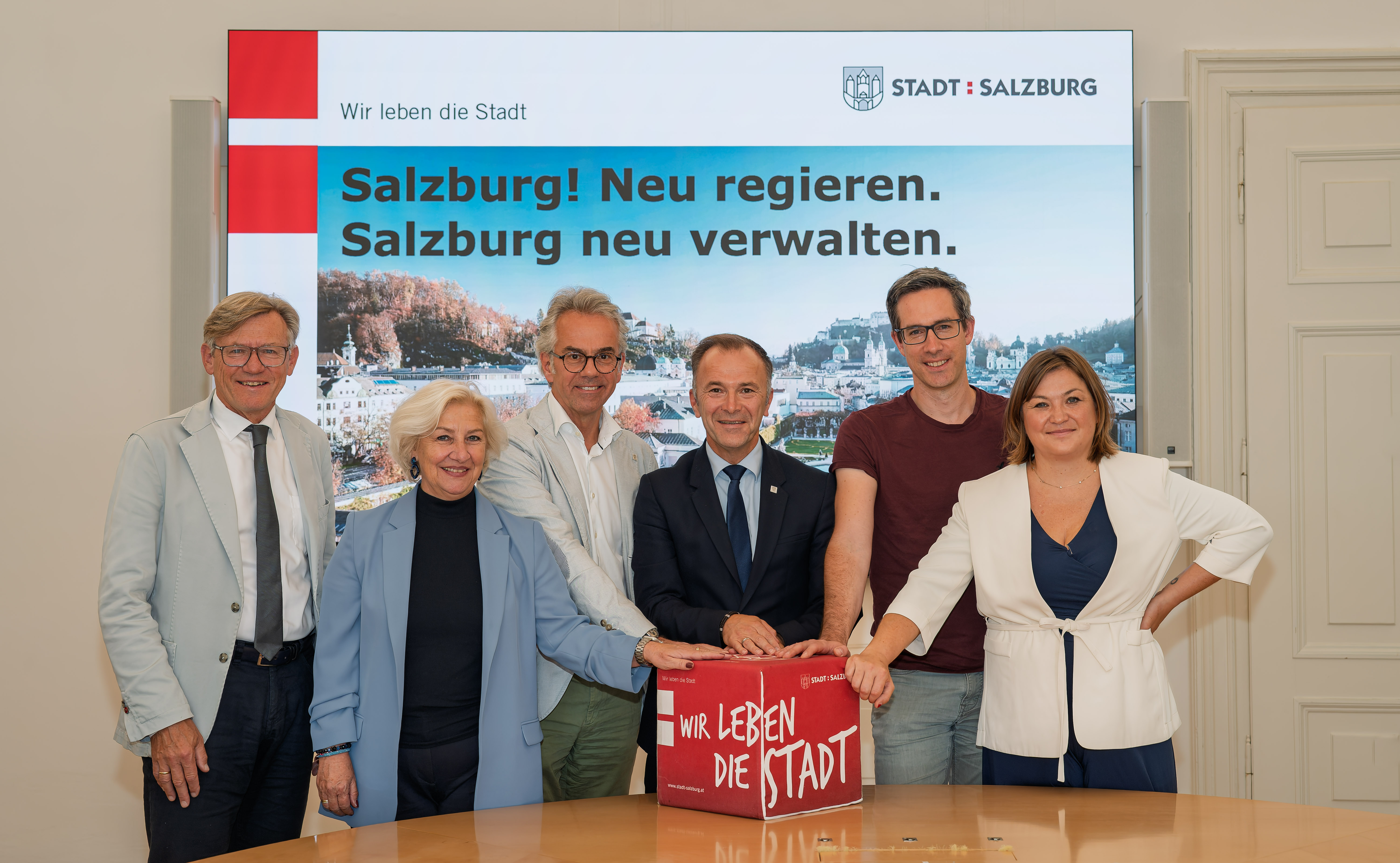 Vor LED-Wall: Magistratsdirektor Max Tischler, Stadträtin Andrea Brandner (SPÖ), Vizebürgermeister Christoph Brandstätter (ÖVP), Bürgermeister Bernhard Auinger (SPÖ), Vizebürgermeister Kay-Michael Dankl (KPÖ) und Stadträtin Anna Schiester (BL/GRÜNE)