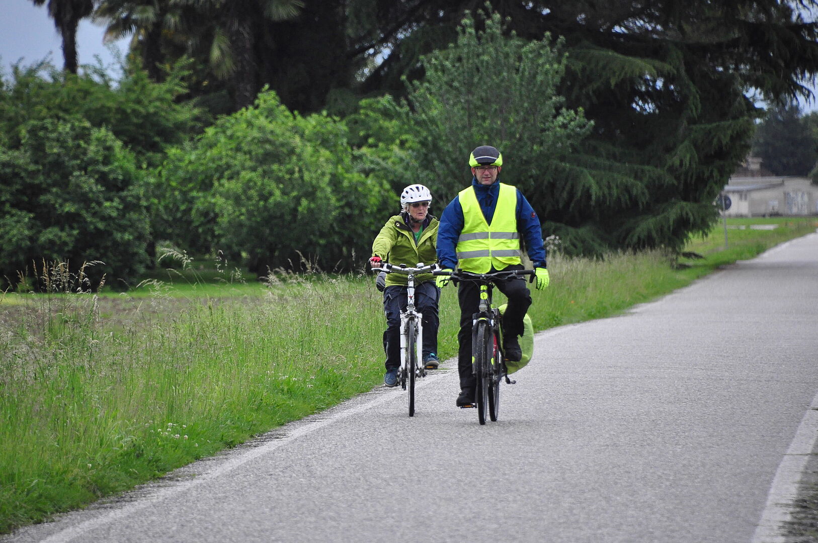 Das Bild zeigt zwei ältere Radfahrer auf einer kleinen Seitenstraße.