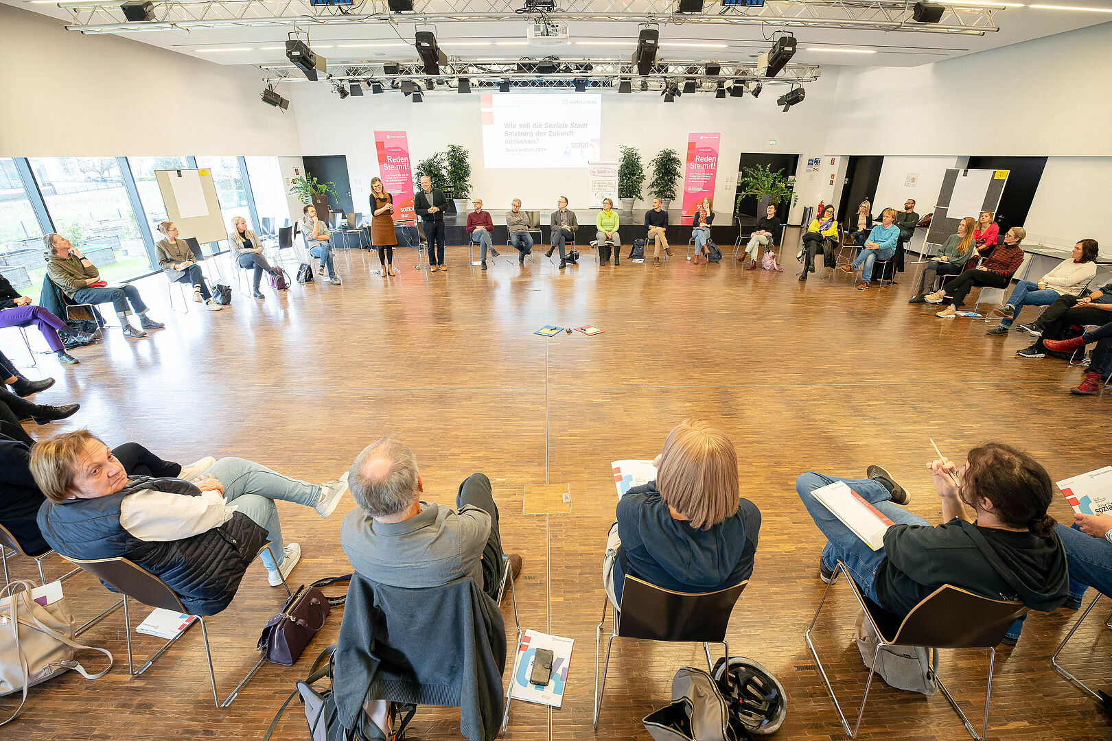 Über 40 Teilnehmer:innen brachten sich zur "Sozialen Stadt" Salzburg ein. 40 Personen sitzen in einem Sessekreis und besprechen ihre Ideen zum neuen Sozialleitbild der Stadt Salzburg.