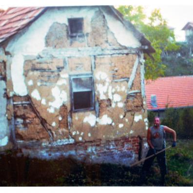 Mann vor einer renovierungsbedürftigen Hausfassade